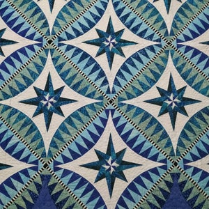 May include: A quilt with a repeating pattern of blue and white stars. The stars are surrounded by a geometric pattern of blue and white triangles.