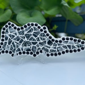 Puede incluir: Arte de pared de mariposa de mosaico en blanco y negro con cuentas negras alrededor de los bordes. La mariposa está montada en un soporte transparente.
