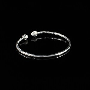 May include: A silver bangle bracelet with a twisted design and pointed ends.