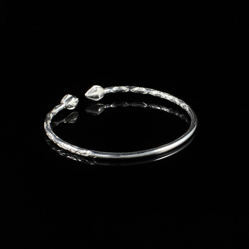 May include: A silver bangle bracelet with a twisted design and pointed ends.
