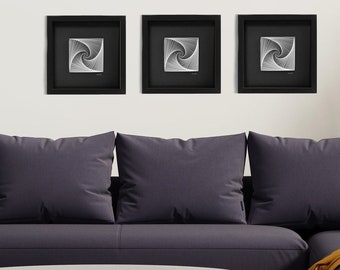 May include: Three square wall art pieces in black frames with white geometric designs. The designs are similar but slightly different. The art pieces are hanging on a white wall above a grey sofa.