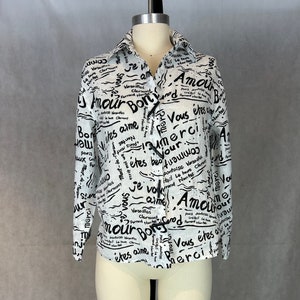Pode incluir: Uma camisa branca de botões com uma estampa em preto e branco de palavras e frases francesas, incluindo "Amour", "Merci" e "Je vous aime".