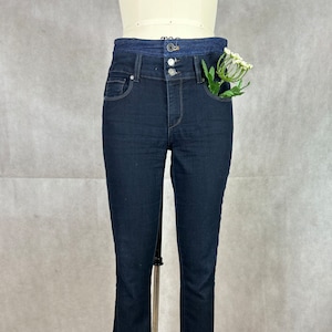 May include: Dark blue denim jeans with a cuffed hem and a contrasting waistband. The jeans have a high waist and a slim fit.