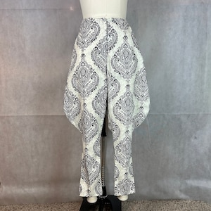 May include: White pants with a black and white paisley pattern. The pants have a wide leg and a high waist.