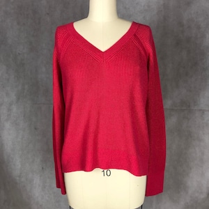 May include: A vibrant red V-neck sweater with long sleeves. The sweater is made of a ribbed knit fabric and is displayed on a mannequin. The number "10" is visible at the bottom of the sweater.