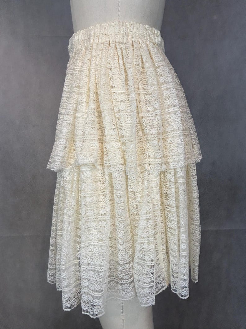 May include: A white lace skirt with multiple layers and a gathered elastic waistband.