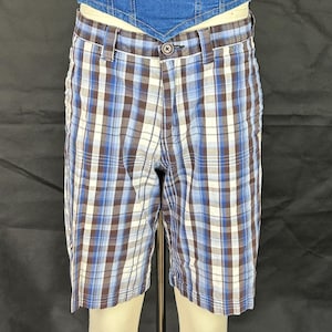 May include: Knee-length shorts in a blue, brown, and white plaid pattern. The shorts have a button closure and belt loops. They appear to be made from a lightweight material. The plaid design is a classic style.