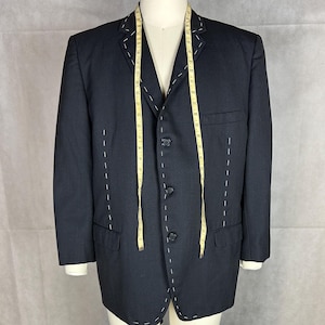 May include: A dark blue blazer with a three-button closure and white stitching detail. The blazer has a tailored fit and is made of a high-quality fabric.