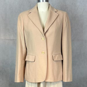 May include: A beige blazer with a single-breasted closure and two front pockets. The blazer has a classic, tailored fit.