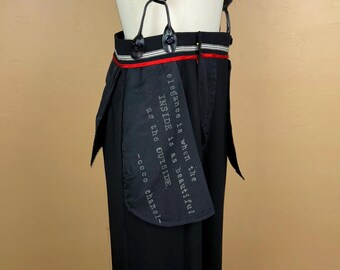 Pantaloni eleganti da uomo neri, ispirati a modelli di design e realizzati con materiali riciclati, con tasche interne foderate con profili rossi e citazione appropriata.