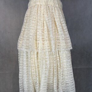 May include: A white lace skirt with a tiered design. The skirt has a gathered waistband and a flowing silhouette.