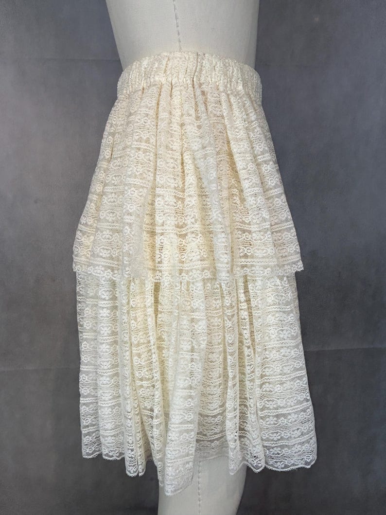 May include: A white lace skirt with a tiered design. The skirt has a gathered waistband and a flowing silhouette.