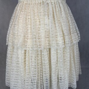 May include: A white lace skirt with a tiered design. The skirt has an elastic waistband and is made of a delicate, sheer fabric.