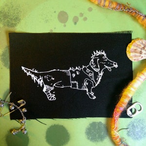 Pode incluir: Um remendo de ferro preto com um contorno branco de um dachshund punk rock vestindo uma jaqueta de couro com tachas e botas.