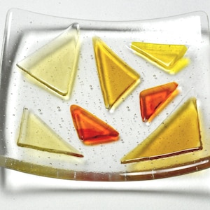 May include: A clear glass dish with a wavy edge, featuring a mosaic of yellow, orange, and red triangular pieces.
