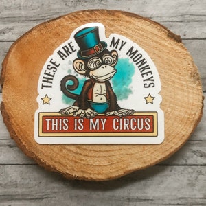 May include: A white sticker with a cartoon monkey wearing a blue top hat and a red and blue outfit. The text on the sticker reads "These are my monkeys. This is my circus."