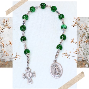 May include: Green and silver rosary with a silver cross and a silver medal of Saint Michael the Archangel.