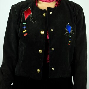 May include: A black suede jacket with gold buttons and colourful embroidered kite designs.