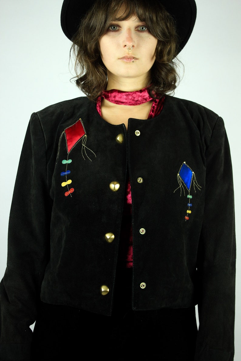 May include: A black suede jacket with gold buttons and colourful embroidered kite designs.