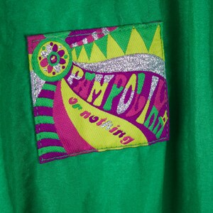 May include: Green jacket with a colourful patch that says "Playful or nothing" in a retro font with silver glitter accents.