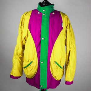 May include: A yellow, green and purple jacket with a snap closure and two zipped pockets. The jacket has a drawstring at the bottom.