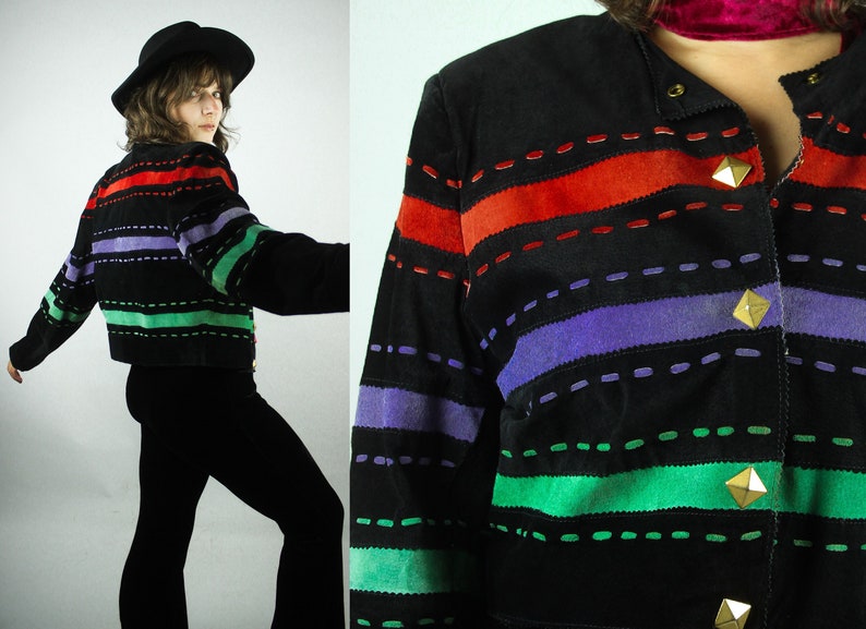 May include: A black suede jacket with colorful striped panels. The jacket has a button closure and gold-toned accents.