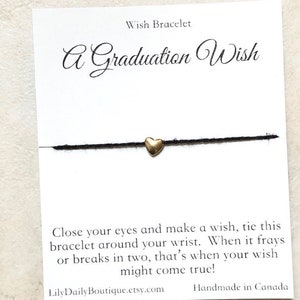 Può includere: Un braccialetto di corda nero con un ciondolo a forma di cuore dorato. La carta recita "A Graduation Wish" e include le istruzioni per legare il braccialetto intorno al polso e fare un desiderio. Quando il braccialetto si sfilaccia o si rompe in due, il tuo desiderio potrebbe avverarsi. La carta include anche il sito web LilyDailyBoutique.etsy.com e indica che il braccialetto è fatto a mano in Canada.