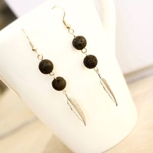 Puede incluir: Un par de pendientes colgantes con cuentas de lava negra y abalorios de plumas plateadas.