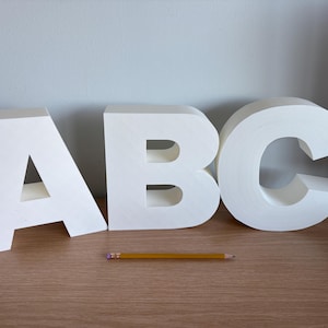 Puede incluir: Letras blancas independientes que deletrean "ABC" sobre una superficie de madera.