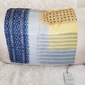 May include: A blue, yellow, and white patterned silk scarf with a West Elm tag attached.