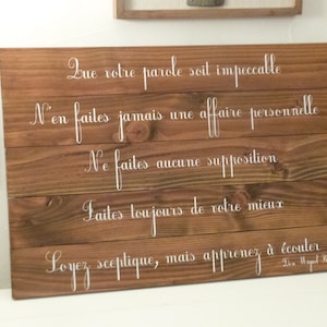 May include: A wooden sign with white lettering that reads: "Que votre parole soit impeccable. N'en faites jamais une affaire personnelle. Ne faites aucune supposition. Laites toujours de votre mieux. Loyez sceptique, mais apprenez &agrave; &eacute;couter. - Don Miguel Ruiz"