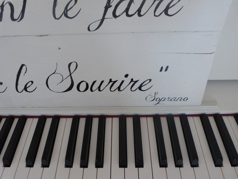 May include: White piano with black keys and the inscription "On le fait le sourire" in black cursive lettering. The inscription "Soprano" is also visible in black cursive lettering.
