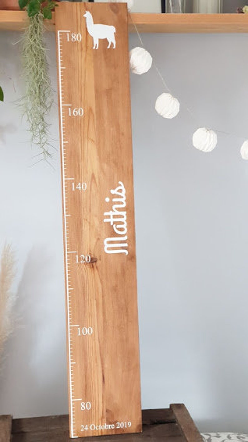 May include: Wooden height chart featuring a white llama and measurement markings. The chart is inscribed with the name "Mathis" and the date "24 Octobre 2019". The chart measures up to 180 cm.