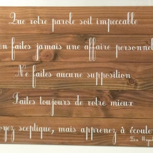 May include: Wooden sign with five white painted lines of text. The text reads: "Que votre parole soit impeccable. N'en faites jamais une affaire personnelle. Ne faites aucune supposition. Faites toujours de votre mieux. Soyez sceptique, mais apprenez &agrave; &eacute;couter. Don Miguel Ruiz."
