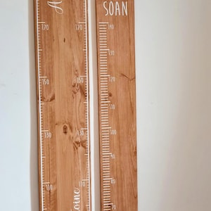 May include: Two wooden height charts with white markings and names. The larger chart, measuring up to 190 cm, has the names "Axel" and "Antoine". The smaller chart, measuring up to 140 cm, has the name "SOAN".