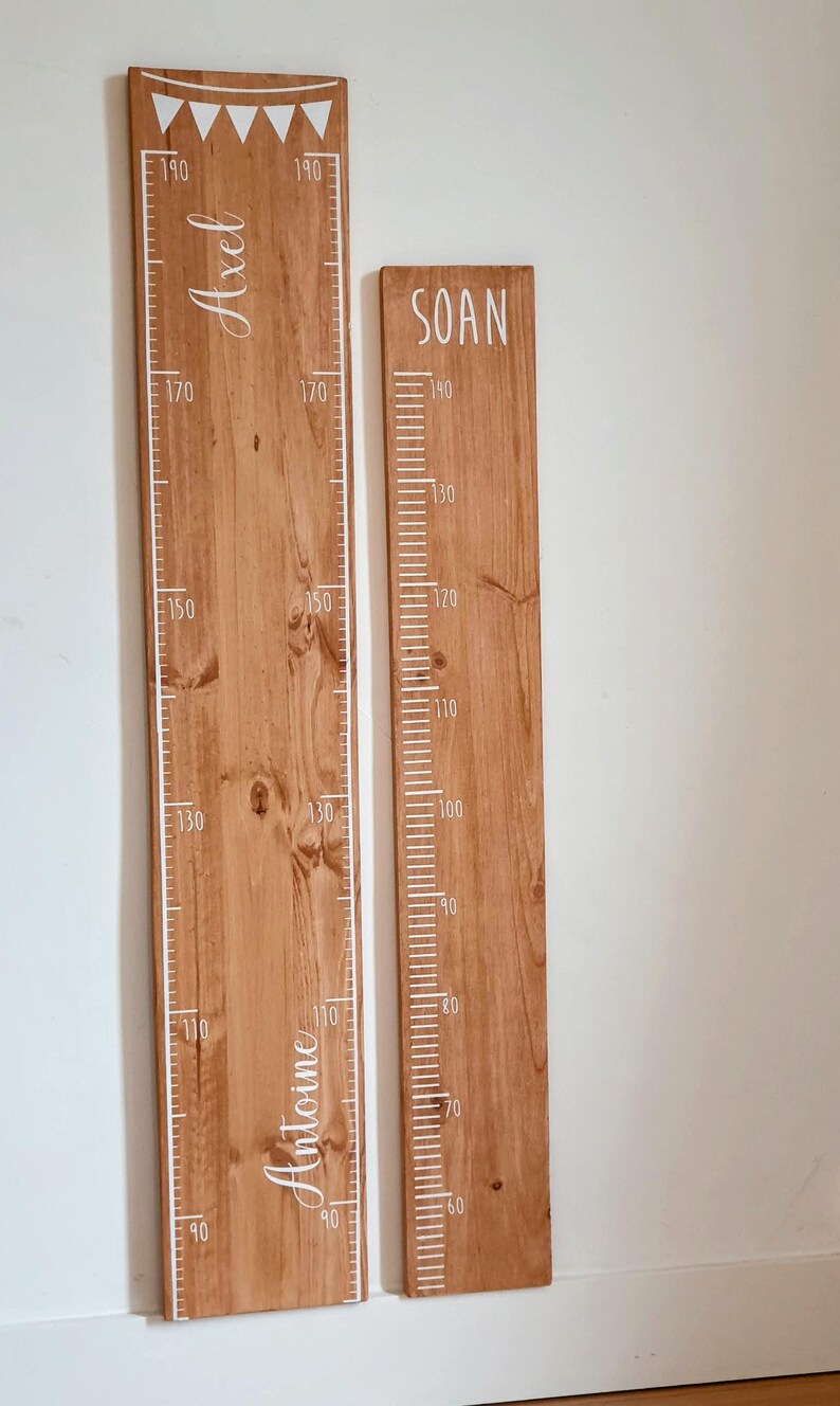 May include: Two wooden height charts with white markings and names. The larger chart, measuring up to 190 cm, has the names "Axel" and "Antoine". The smaller chart, measuring up to 140 cm, has the name "SOAN".