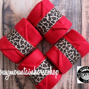Può includere: Quattro fasce per le gambe dei cavalli di colore rosso con un bordo a stampa leopardata. Le fasce sono disposte a forma di quadrato. Il testo "@snowymtnhorseshop" è visibile nell'angolo in basso a sinistra dell'immagine. Un cerchio bianco e nero con il testo "Made in Montana USA" è visibile nell'angolo in basso a destra dell'immagine.