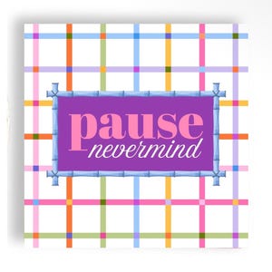 May include: A square wall art piece featuring a white background with a colorful grid of intersecting orange, pink, blue, yellow, and green lines. A central purple rectangular frame with a bamboo-style border contains the text pause nevermind.