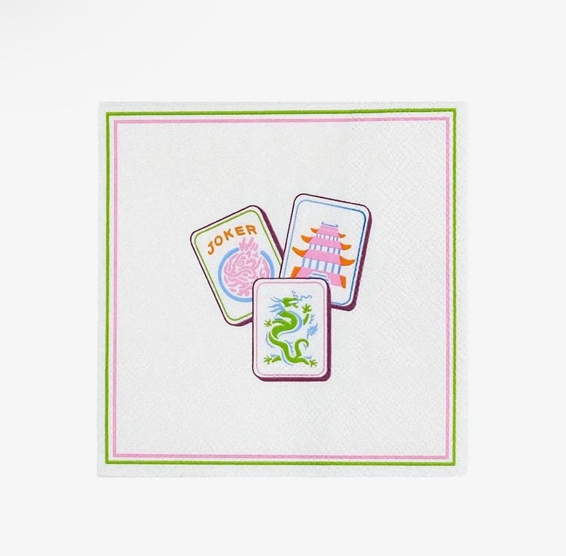 K&ouml;nnte beinhalten: Wei&szlig;es quadratisches Papierservietten mit einem rosa und gr&uuml;nen Rand. Die Serviette zeigt drei farbenfrohe Kartenillustrationen: eine Jokerkarte, eine Pagodenkarte und eine Drachenkarte.