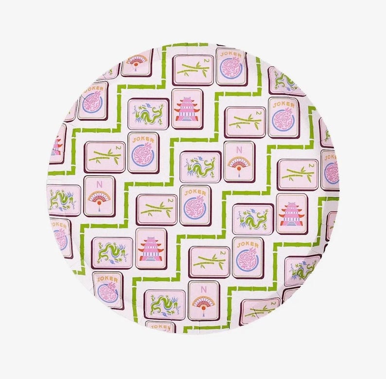 May include: A round, white tray with a repeating pattern of pink Mahjong tiles, green bamboo-like lines, and various symbols. The tiles feature dragons, pagodas, fans, and the word "Joker".