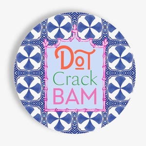 May include: A circular decorative plate featuring a blue and white geometric tile pattern. In the center, a light blue rectangular panel is framed by a pink bamboo-style border, displaying the text "DoT Crack BAM" in orange, green, and pink.