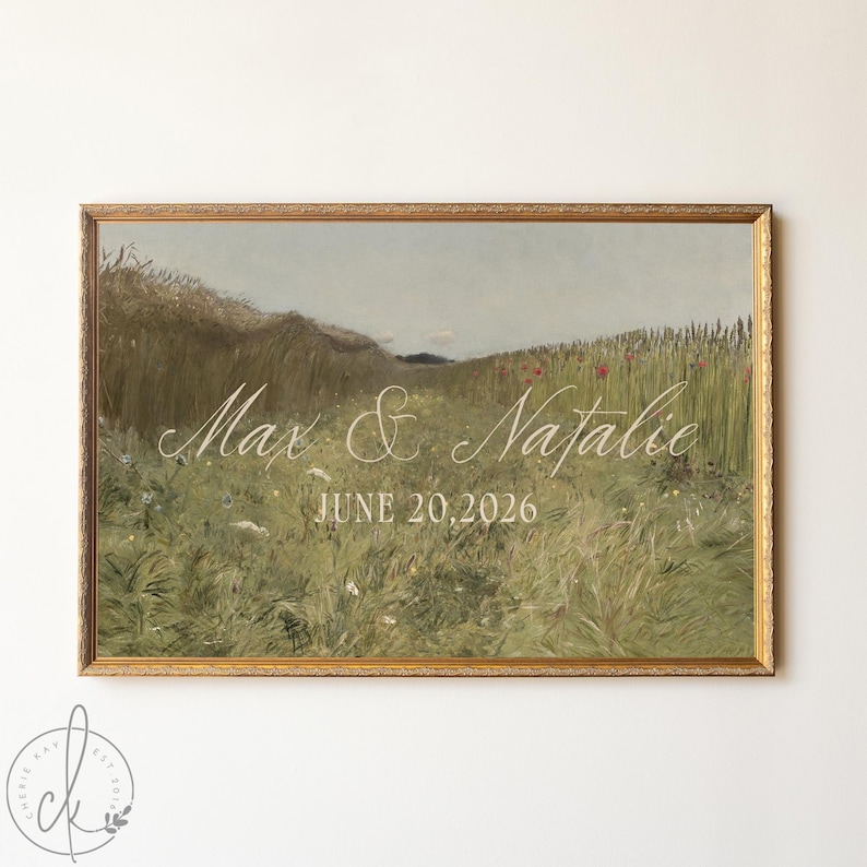 May include: A rectangular landscape print in a gold frame featuring a grassy field with wildflowers under a muted sky. The text Max & Natalie is written in white script, followed by the date JUNE 20, 2026, in a clean, white sans-serif font.