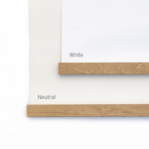 K&ouml;nnte beinhalten: Zwei rechteckige H&auml;ngevorrichtungen mit hellbraunen Holzleisten oben und unten. Die obere Vorrichtung hat einen wei&szlig;en Hintergrund mit der Aufschrift White, die untere einen neutralen, cremewei&szlig;en Hintergrund mit der Aufschrift Neutral.