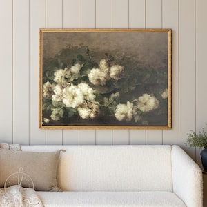 May include: A vintage-style painting of a bouquet of white roses with green leaves against a dark brown background. The painting is framed in a gold frame.