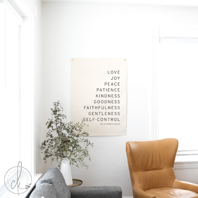 May include: A beige canvas print with black text listing the fruits of the spirit: love, joy, peace, patience, kindness, goodness, faithfulness, gentleness, and self-control. The text also includes the scripture reference Galatians 5:22-23.