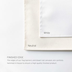 May include: Two fabric swatches, one white and one a neutral cream color. The edges of the fabric are neatly hemmed. The text "Finished Edge" is below the swatches. The text reads: "The edges of our flag banners and dowel rod canvases are carefully hemmed in-house to ensure a high-quality finished product."