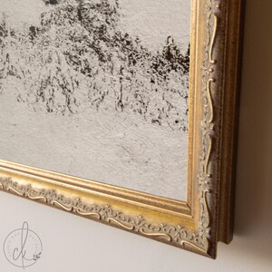 May include: A framed artwork with a gold ornate frame. The artwork features a black and white abstract landscape. The frame has a detailed, vintage design. The artwork is mounted on a light-colored wall.