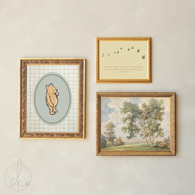 May include: Three framed artworks with gold frames are displayed on a light wall. One features a Winnie the Pooh illustration, another has a quote, and the third is a landscape painting. The frames have decorative detailing.