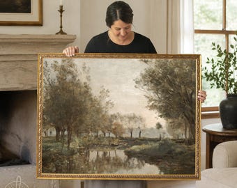May include: A rectangular landscape painting in a gold ornate frame depicting a calm river scene with trees and foliage in muted earth tones of brown, green, and grey. The artwork features a reflective water surface and a soft, overcast sky.