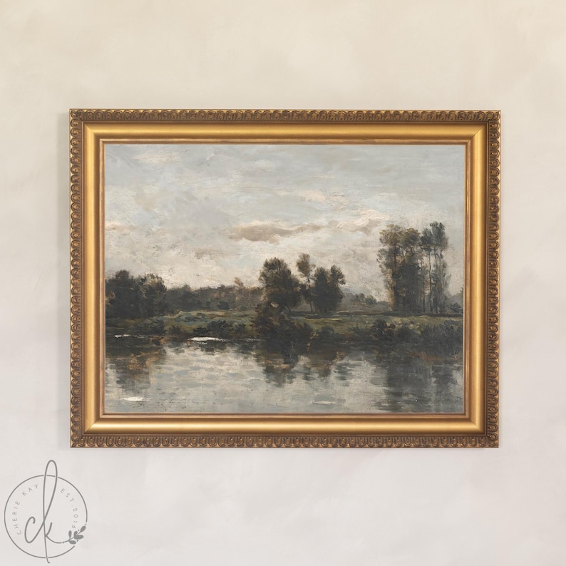 May include: A framed landscape painting with a gold ornate frame. The artwork depicts a serene river scene with trees and a cloudy sky. The painting's colors are muted, with shades of green, gray, and brown.